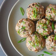 a white plate topped with meatballs covered in sauce and garnished with green onions