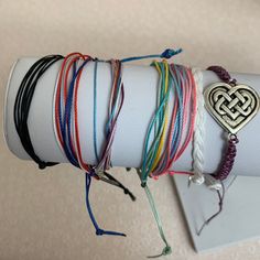 several bracelets are stacked on top of each other with a heart shaped pendant hanging from the middle