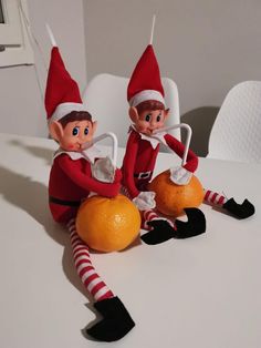 two elfs sitting on top of an orange