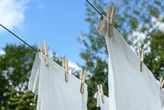 clothes hanging on the clothesline outside with trees in the backgroung and blue sky in the background