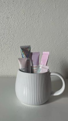 a white cup filled with cosmetics on top of a table