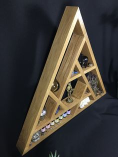 a wooden shelf with various items in it on a black surface next to a succulent plant