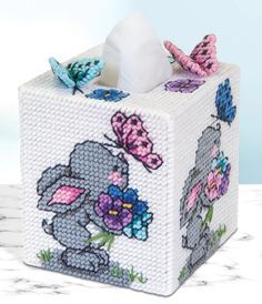 a tissue box with an elephant and butterfly design on the front, sitting on a marble surface