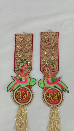 two pairs of earrings with tassels hanging from the side, decorated in gold and red