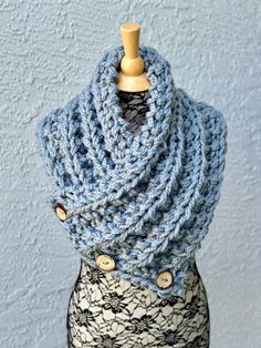 a crocheted cowl with buttons on the front and side, sitting on top of a mannequin