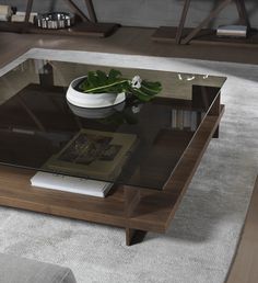 a coffee table with a glass top and wooden legs, sitting on a rug in a living room