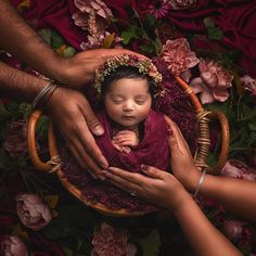 a newborn baby wrapped in a red blanket is held by her mother's hands