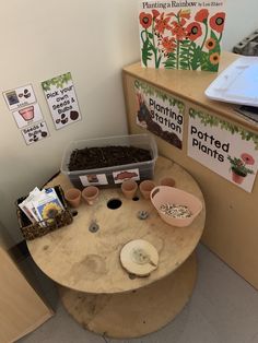 a wooden table topped with lots of dirt next to a flower pot filled with plants