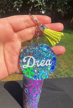 a hand holding a keychain with the word dream on it and a tassel