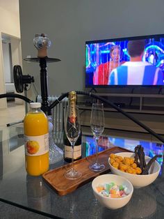 a table topped with bowls and glasses filled with food next to a flat screen tv