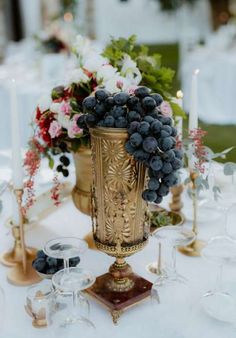 a table topped with a vase filled with lots of grapes