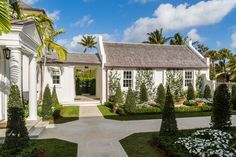 a white house with lots of trees and bushes around it's front entrance area