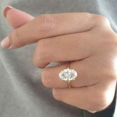 a woman's hand wearing a ring with a diamond on the middle and side