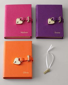 three different colored notebooks with heart shaped clips attached to the front and back covers