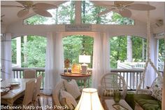 a living room filled with lots of furniture next to a window covered in white curtains