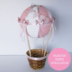 a basket filled with pink and white cake toppers next to a cupcake on a stick