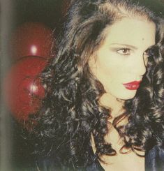 a woman with long curly hair and red lipstick