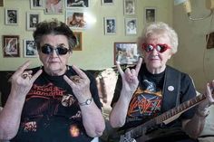 two women sitting on a couch with their hands in the air and one holding an electric guitar