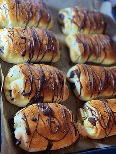 several rolls with chocolate drizzled on them sitting in a baking pan, ready to be eaten