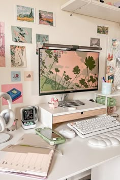 a desk with a computer monitor, keyboard and headphones