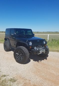 a black jeep parked on top of a dirt road