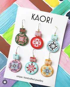 four different colored ornaments are hanging from earrings