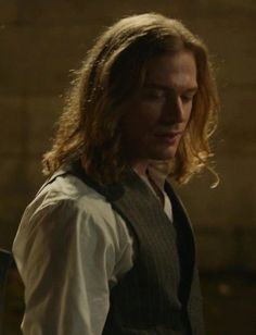 a man with long hair wearing a vest