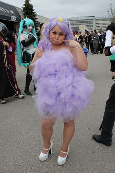 a woman in a purple dress is posing for the camera with her hands on her hips