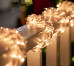 some white candles with lights on them near a christmas tree