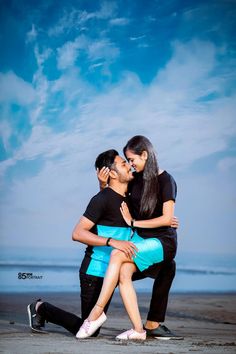 a man and woman kissing on the beach with blue skies in the backgroud