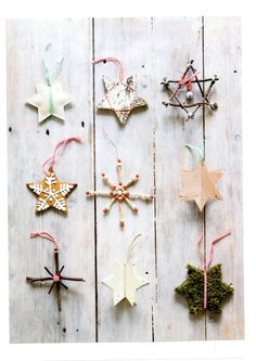 christmas ornaments are hanging on a white wooden wall with pink and green string attached to them