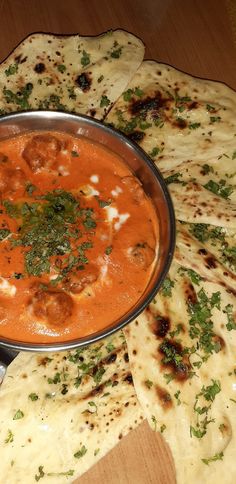 a pan filled with food sitting on top of a table next to pita bread