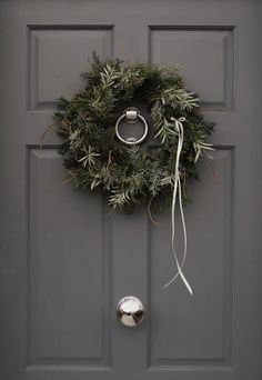 a wreath on the front door with a ring hanging from it's center loop