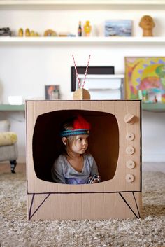 a little boy wearing a red hat sitting in front of a small television set on the floor