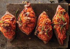 four pieces of bread with meat and vegetables on them sitting on a wooden cutting board