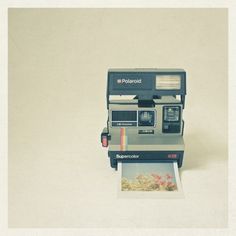 an old polaroid camera sitting on top of a polaroid print