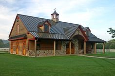 a large wooden building with a metal roof and two dormers on the top floor