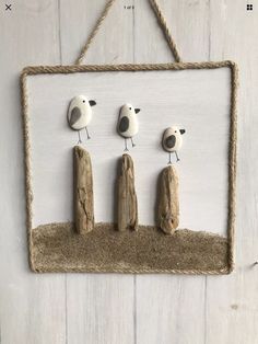 three little birds sitting on top of a piece of driftwood in front of a white wall