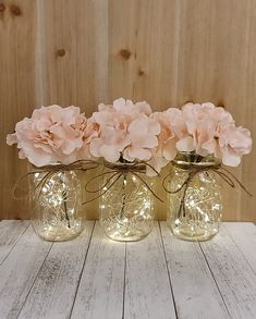 three mason jar vases with flowers in them