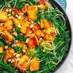 a pan filled with chicken and greens on top of a table