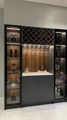 a wine cellar with many bottles and glasses in it's display case, as well as several empty glassware