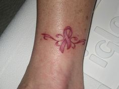 a small pink ribbon tattoo on the foot of a woman's left arm and wrist