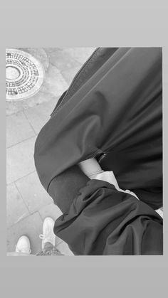 a black and white photo of someone's feet with a coat on