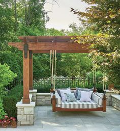 a wooden swing bed sitting under a pergoline covered arbor with pillows on it