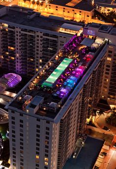 an aerial view of a city at night with buildings lit up in purple and green