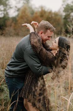 a man and woman hugging in the middle of tall grass with trees in the background