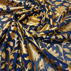 a blue and gold floral print fabric with large leaves on the side, in very close up