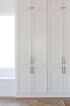 an empty room with white cupboards and carpet on the floor in front of a window