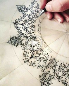 someone is drawing on the paper with a pen and inking it in order to create an intricate design