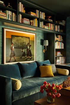 a living room filled with furniture and bookshelves next to a painting on the wall